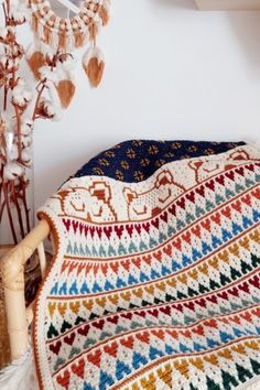 a crocheted blanket sitting on top of a bed next to a vase with flowers