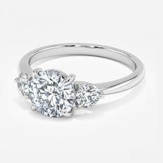 three stone engagement ring with diamonds on the sides and an oval diamond in the center