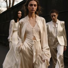 three women in white outfits walking down the street with their hands on their hipss