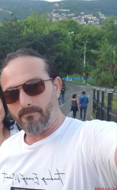 a man and woman taking a selfie with trees in the background