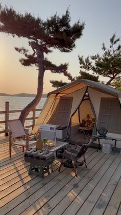 a tent set up on a wooden deck next to the ocean