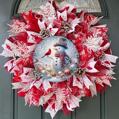 a red and white christmas wreath with a snowman on it's front door