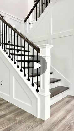 a white staircase with black handrails and wood flooring in a home setting