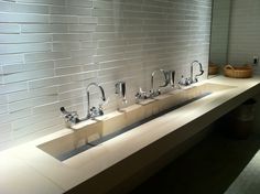 a row of sinks in a bathroom with white tiles on the wall and flooring