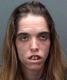 a young man with long hair is looking at the camera while wearing a gray shirt