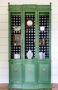 a green china cabinet with black and white wallpaper