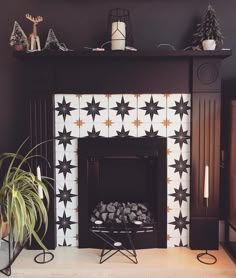 the fireplace is decorated with black and white stars on it's mantle, along with two potted plants