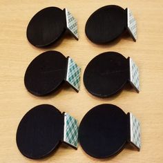 six pieces of black and white paper with green checkered ribbon on them sitting on a wooden surface