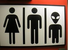 a bathroom sign with an alien and man in the center, on a red wall