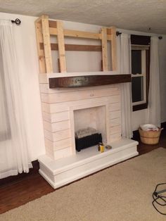 a living room with a fire place in the middle and curtains on the other side