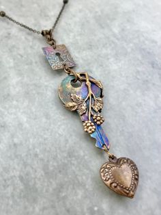 a necklace with a heart shaped pendant on it's end and two charms attached to the chain