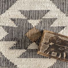 an elephant carved into the side of a piece of wood on top of a rug