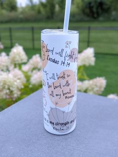 a cup with a straw in it sitting on top of a table next to flowers