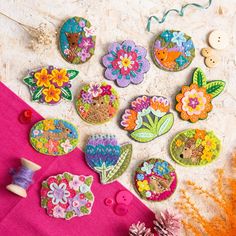 several embroidered flowers and buttons on a pink cloth