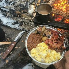 a person holding a bowl of food over an open fire