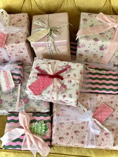 many wrapped presents are stacked on top of each other in pink and green colors with bows