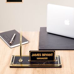 a wooden desk topped with a laptop computer next to a plaque that says james bryant manager