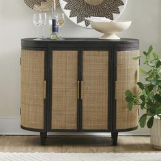 a round mirror sitting on top of a wooden cabinet next to a potted plant