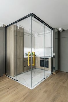 an empty kitchen with glass walls and wooden floors