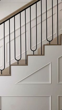 a white staircase with black railing and wooden handrails in a home setting on the floor