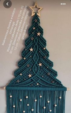 a crocheted christmas tree hanging on a wall next to a wooden star decoration