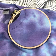 a purple shirt with a gold hoop on it