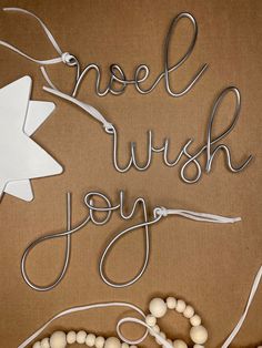 the words noel wish joy are made out of wire and beads on a brown background