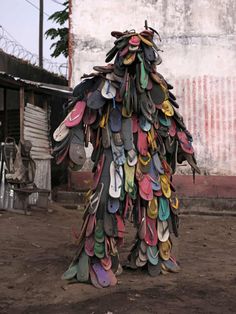 a large pile of shoes sitting on top of a dirt field next to a building