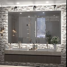 a bathroom with two sinks and a large mirror on the wall above it is lit by lights