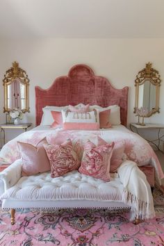 a bed with pink and white pillows on top of it next to a rug in front of a mirror