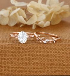 two wedding rings sitting next to each other on top of a piece of cloth with flowers in the background