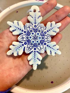 a hand holding a blue and white snowflake ornament