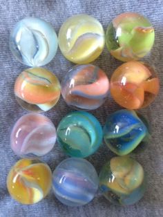 several different colored marbles sitting on top of a gray cloth covered floor next to each other