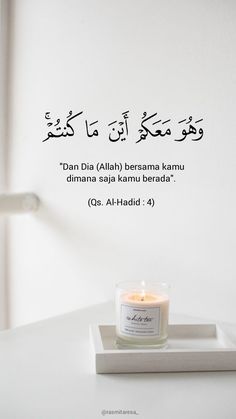 a candle sitting on top of a white table next to a wall with arabic writing