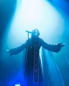 a man standing on top of a stage with his arms outstretched in front of him