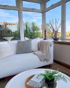 a living room filled with white furniture and large windows overlooking the cityscape in the distance