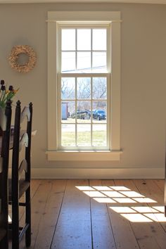 the sun shines through an open window in a room with wooden floors and white walls