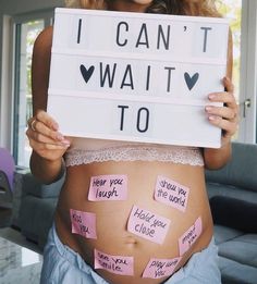 a pregnant woman holding up a sign that says i can't wait to