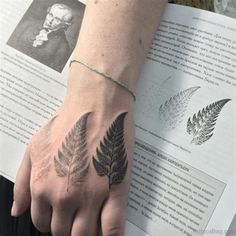 a person's hand with a tattoo on it and an open book in the background