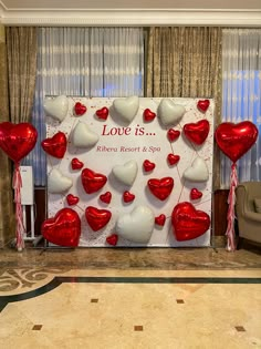 a red and white backdrop with heart balloons