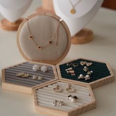 four pairs of earrings are sitting on the table next to an earring holder and ring box