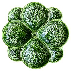 a green flower shaped dish sitting on top of a white table