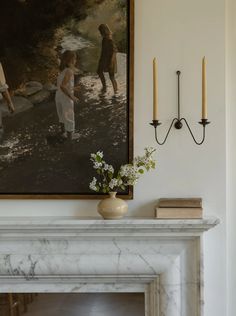 a painting on the wall next to a fireplace with candles and flowers in front of it