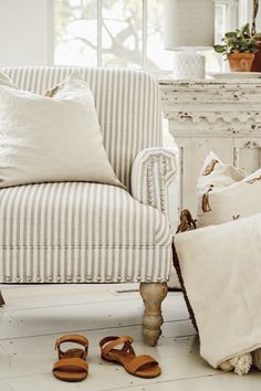 a pair of sandals sitting on the floor next to a striped chair and footstool