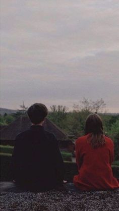 two people sitting on the ground looking at something in the sky