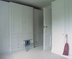 an empty room with white closets and clothes hanging on the doors, in front of a mirror