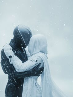 two people dressed in winter clothing embracing each other with snow falling around them and behind them