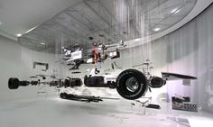 an artistic photo of a car in the middle of a room with white walls and flooring