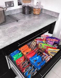 an open drawer in a kitchen filled with snacks and candy bar flavors on the counter