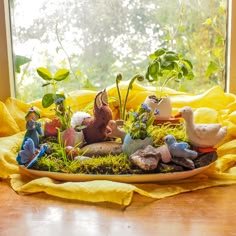 an arrangement of small figurines sitting on a plate in front of a window